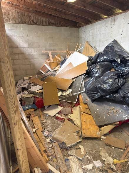 Shed interior packed floor-to-ceiling with debris, furniture, and bagged trash before JCE cleanout