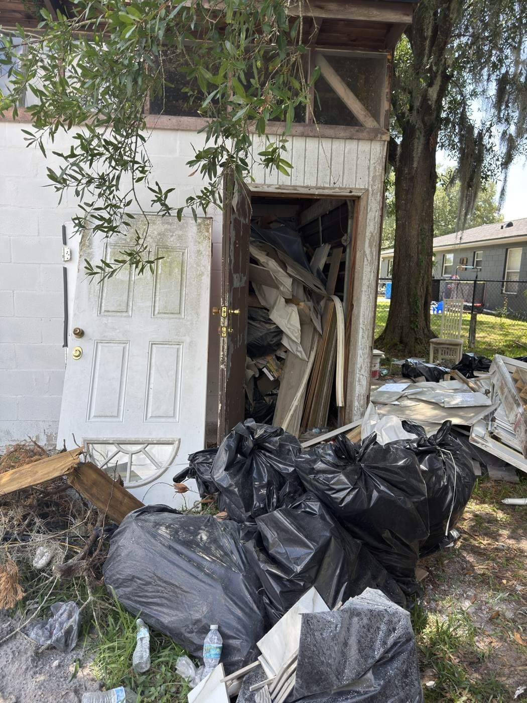 Shed exterior packed with bagged junk and debris before cleanout
